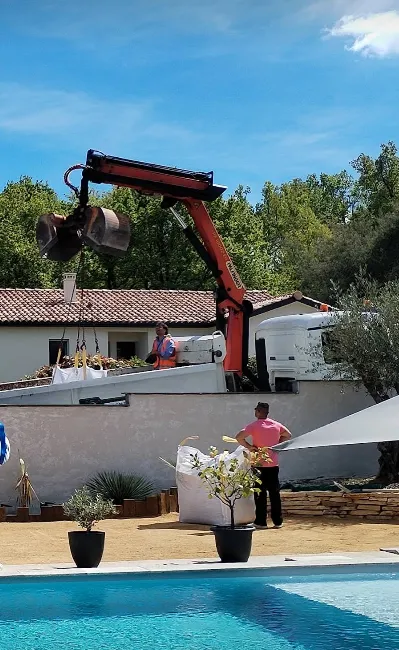 Camion grue SolPur déposant un big bag derrière un mur